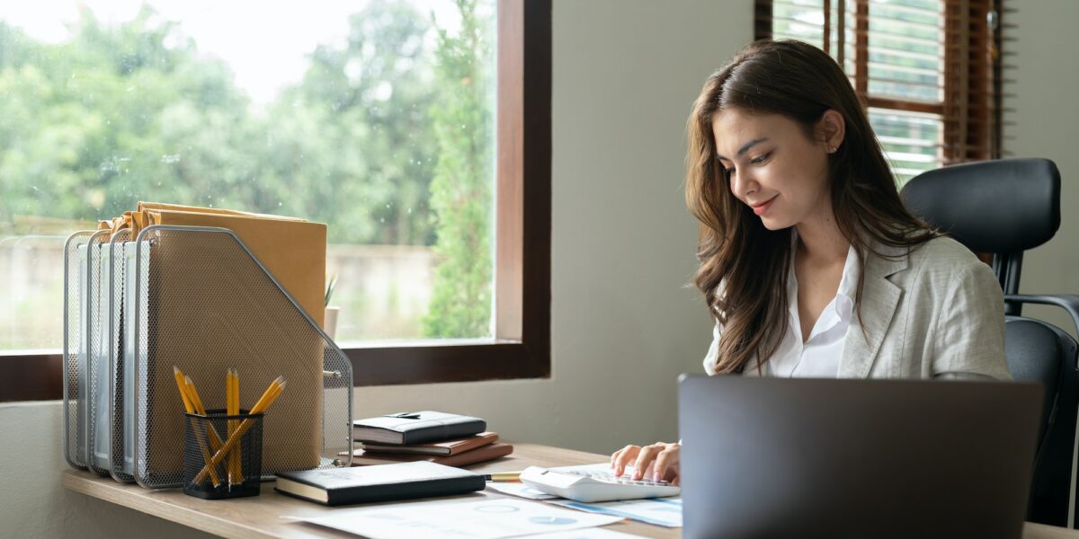 Woman accountant using calculator and computer in office, finance and accounting concept.