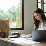 Woman accountant using calculator and computer in office, finance and accounting concept.