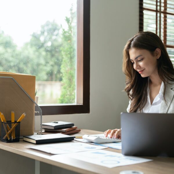 Woman accountant using calculator and computer in office, finance and accounting concept.