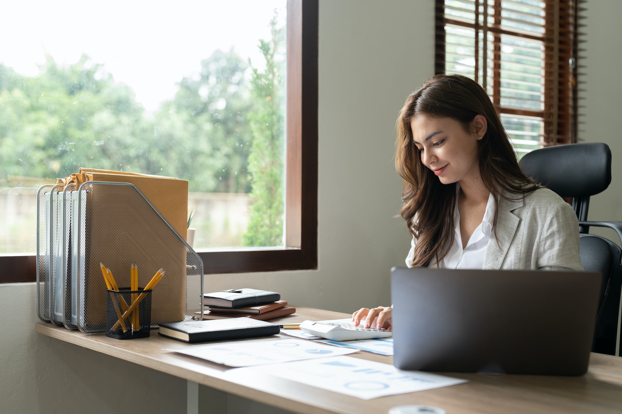 Woman accountant using calculator and computer in office, finance and accounting concept.